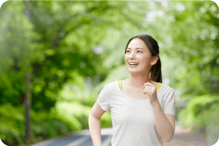 緑豊かな公園を歩く女性